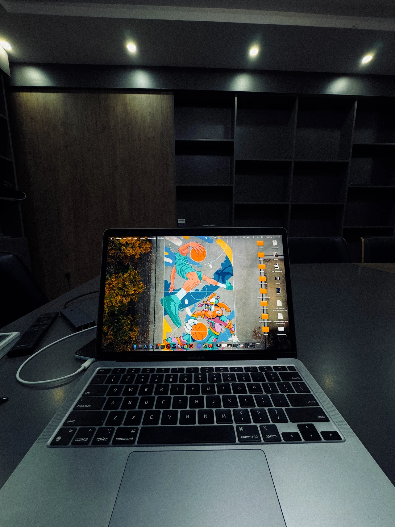 A laptop glowing on a table in a dimly lit room with empty shelves.