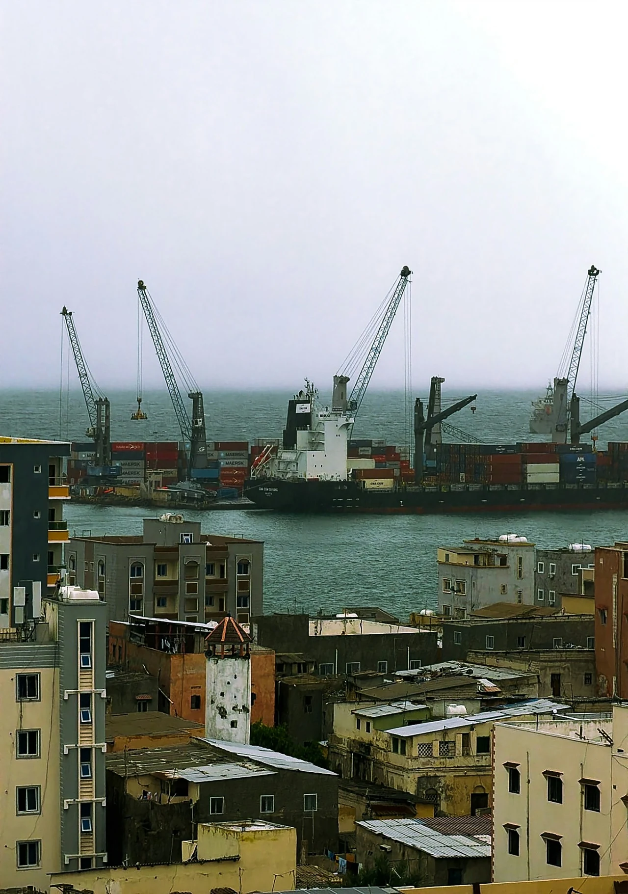 Harbour cranes beyond buildings and rooftops.