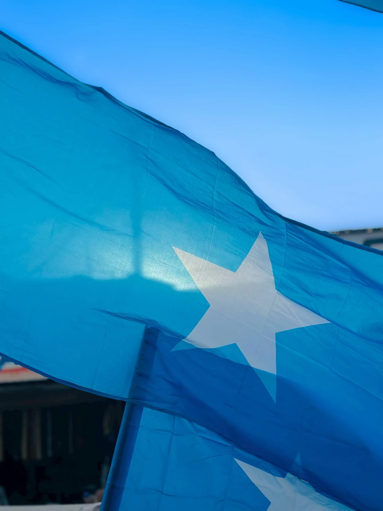 A blue Somali flag with a white star against the sky.