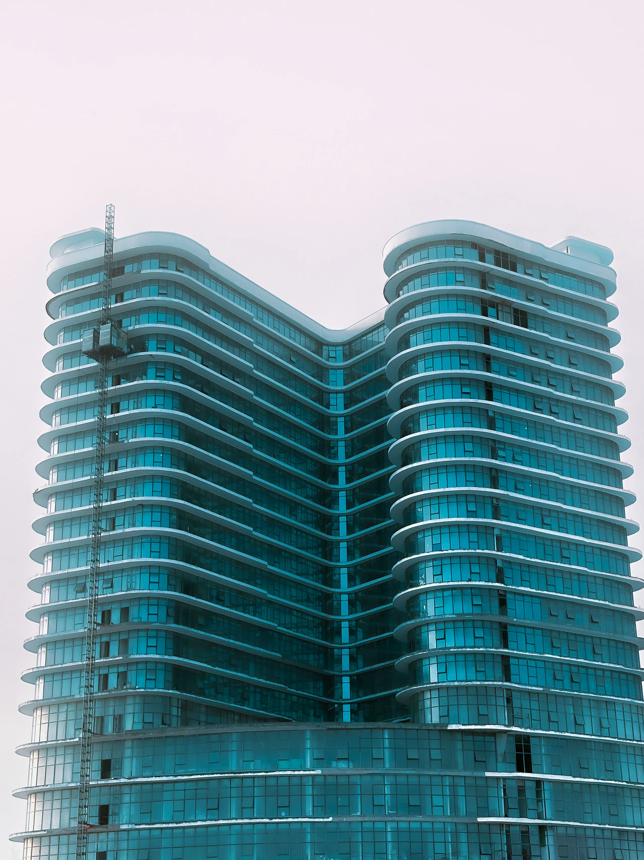Curved balconies and blue glass across the facade of a high-rise building.