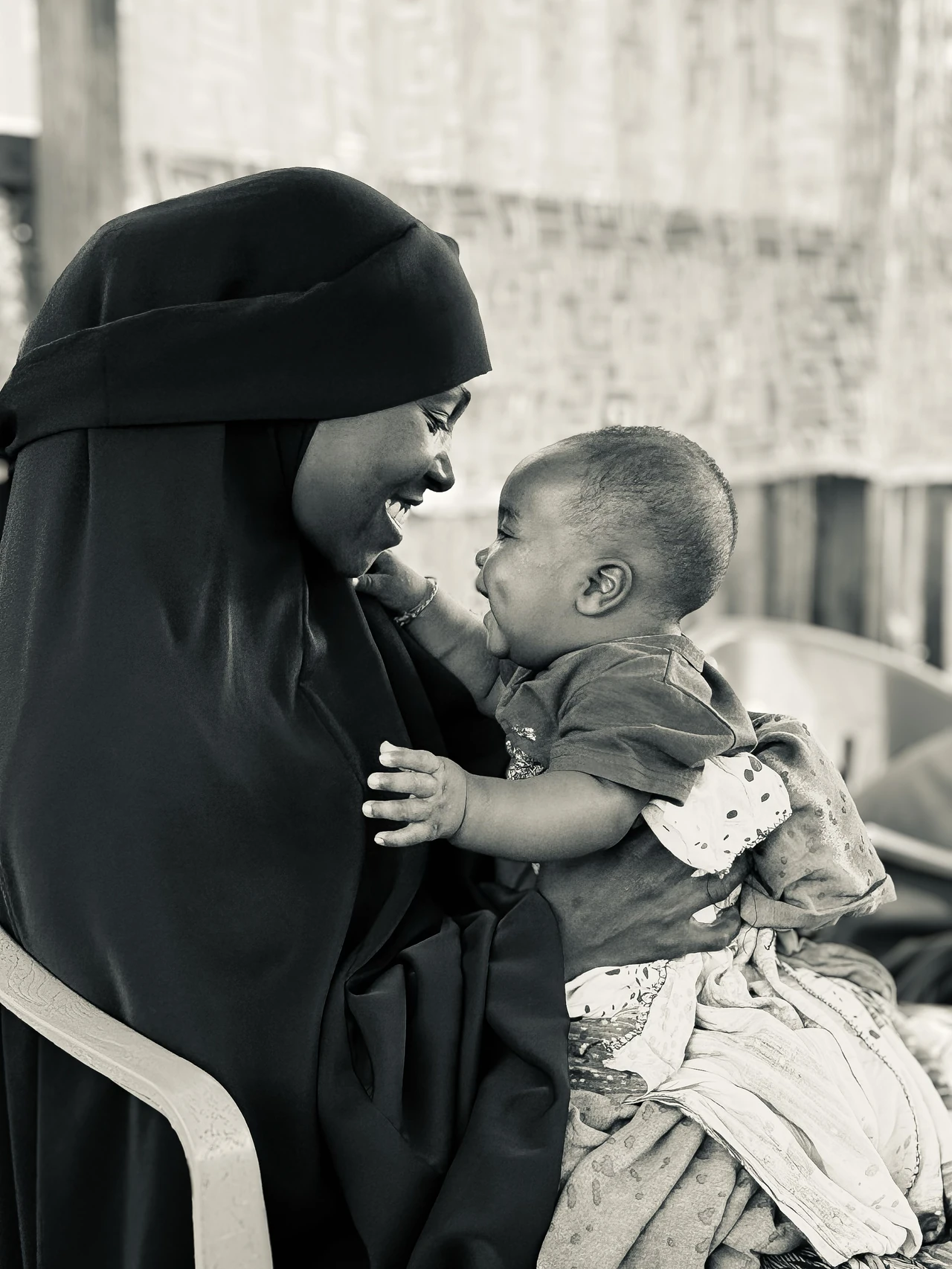 A woman holding a smiling child, photographed in black and white.