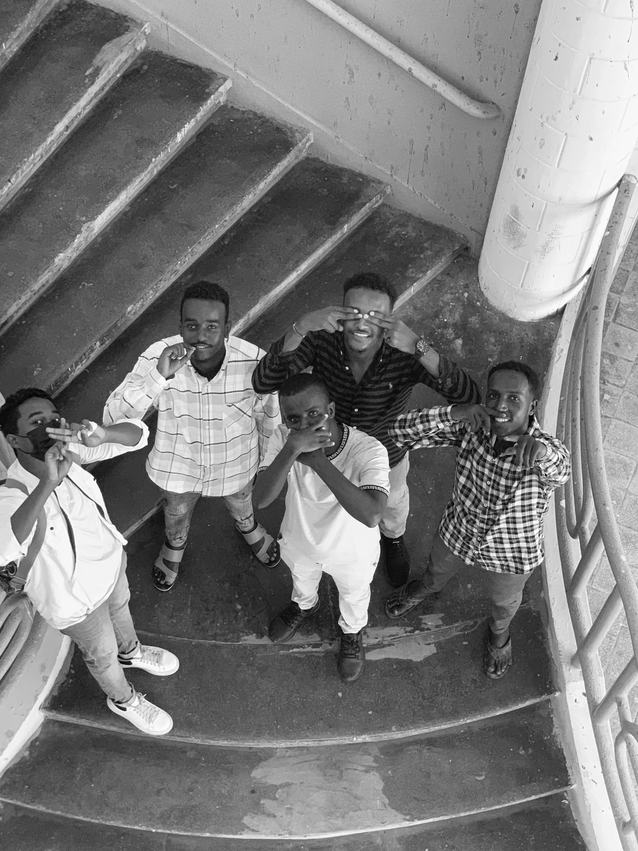 A group looking up from a curved stairwell in black and white.