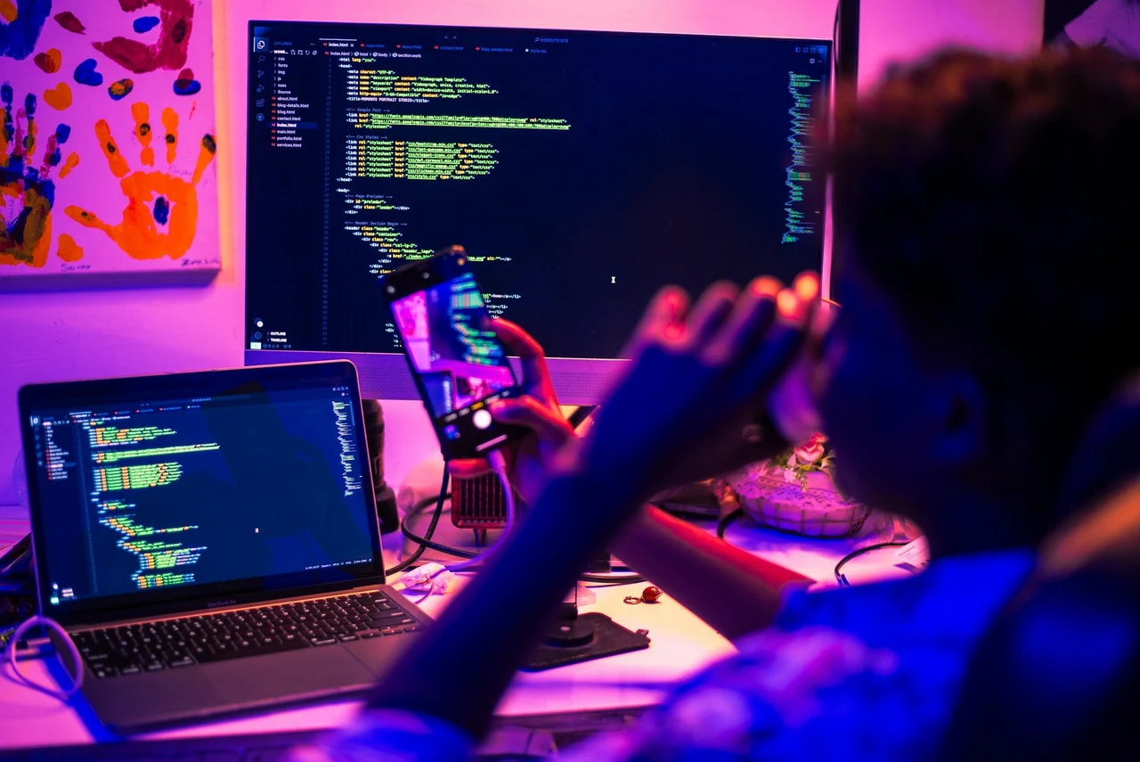 A person working at a computer in blue and purple light.