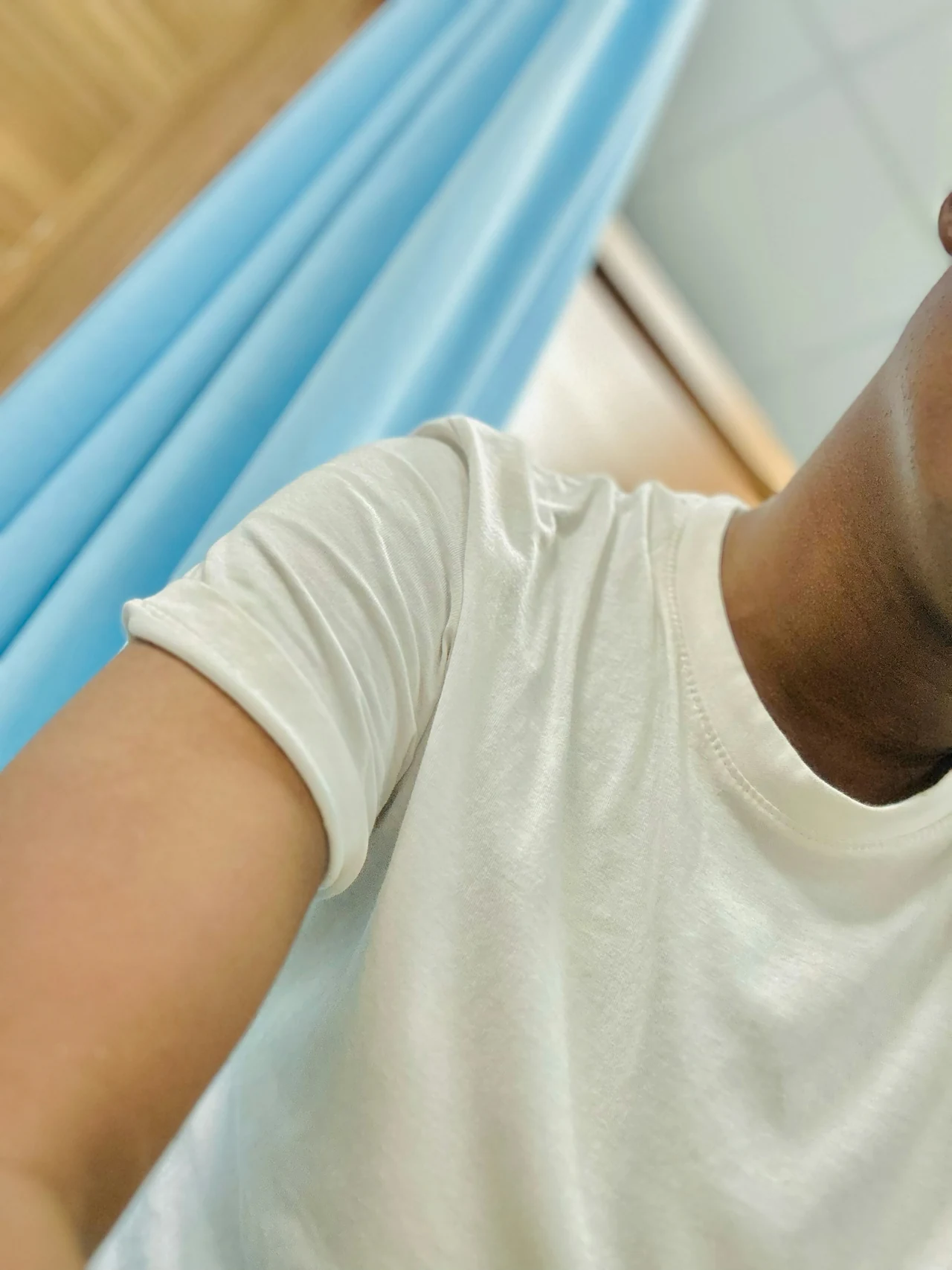 A close crop of a white shirt beside pale blue curtains.