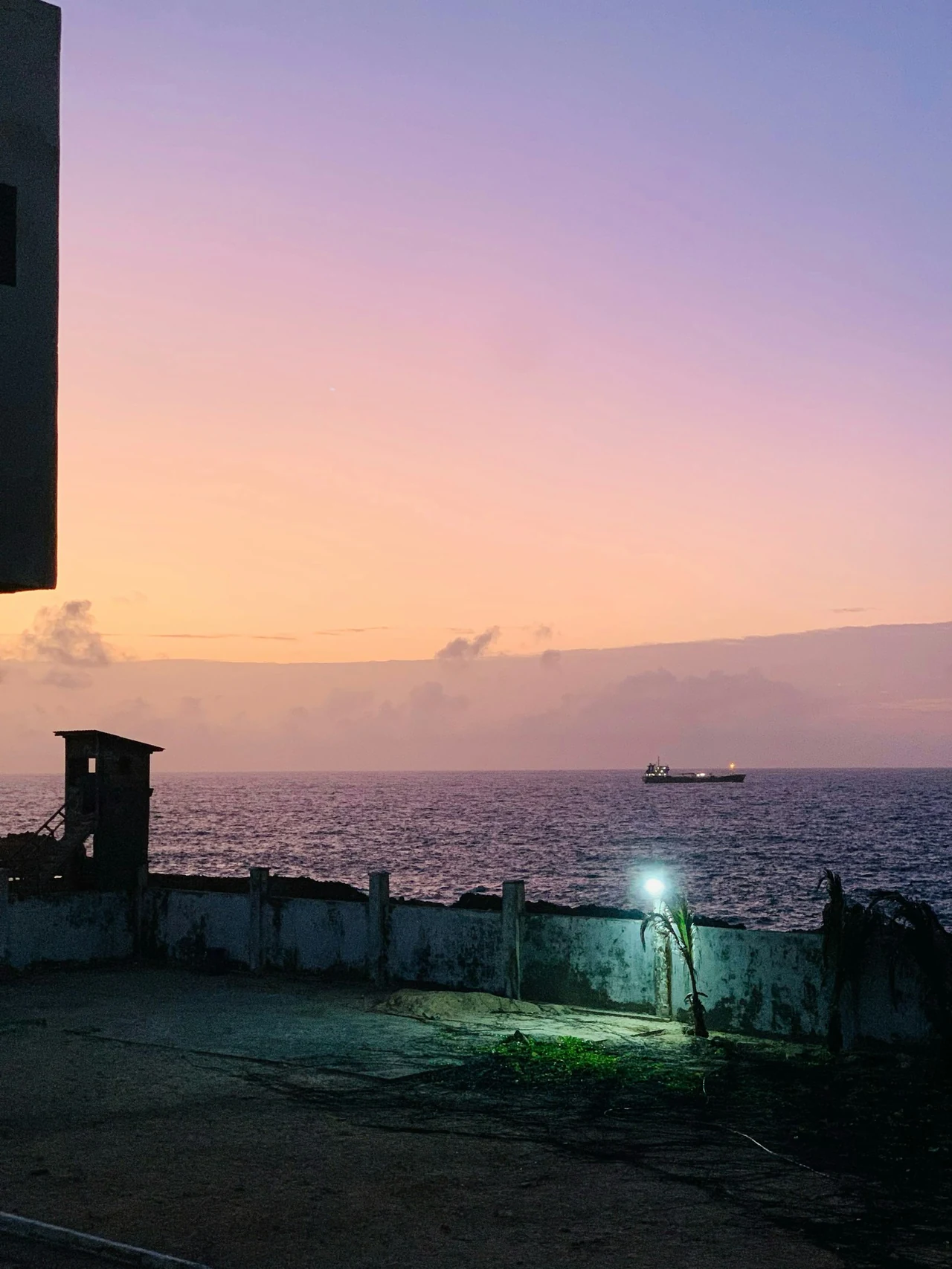 A pink evening sky above the ocean and a rooftop terrace.