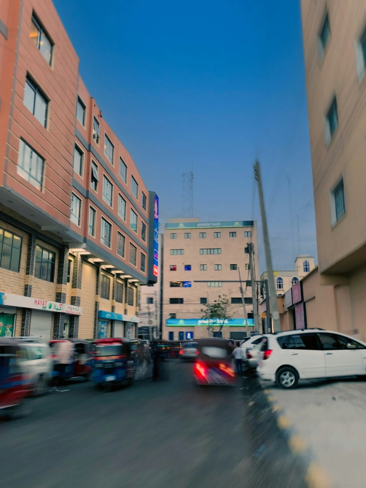 Buildings and traffic along a sunlit urban street.